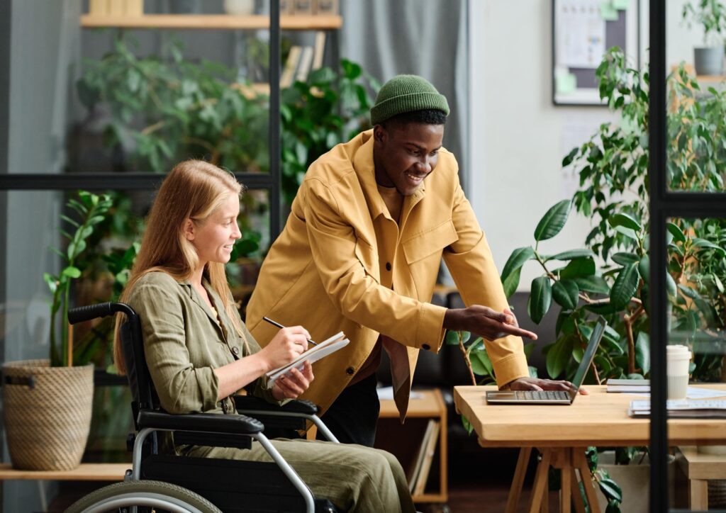 Two event planners organizing a sustainable conference on a laptop.