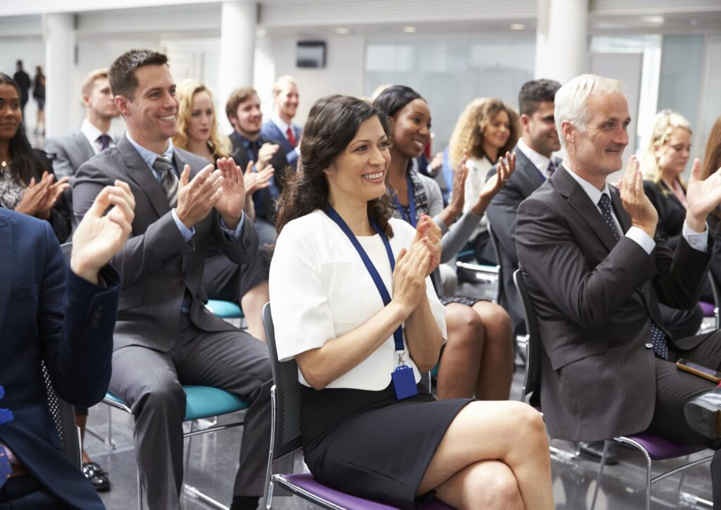 Attendees clapping their hands during a scientific conference.